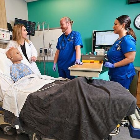 Nursing instructor teaching nurse students on pediatric mannequin in simulation center at joyce university campus