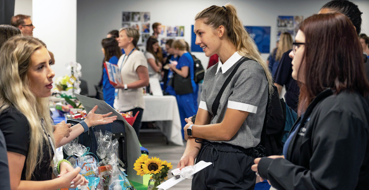 Young professionals standing at a booth at the joyce university career fair