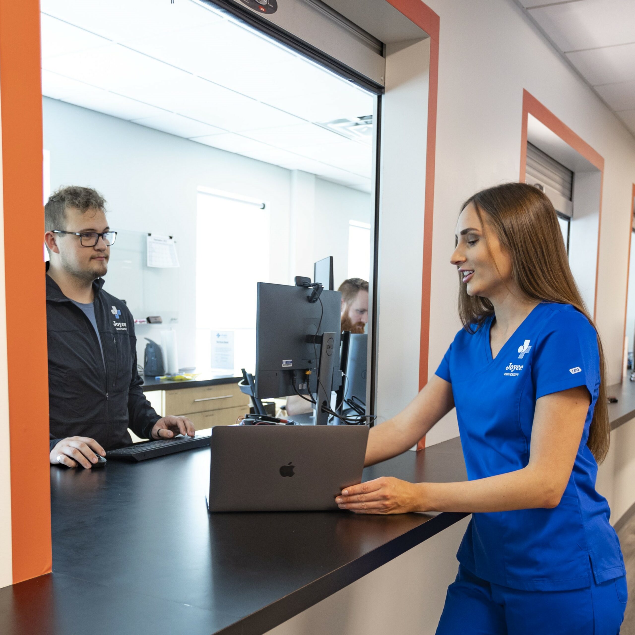 nursing student standing at IT Support window with laptop on joyce university campus