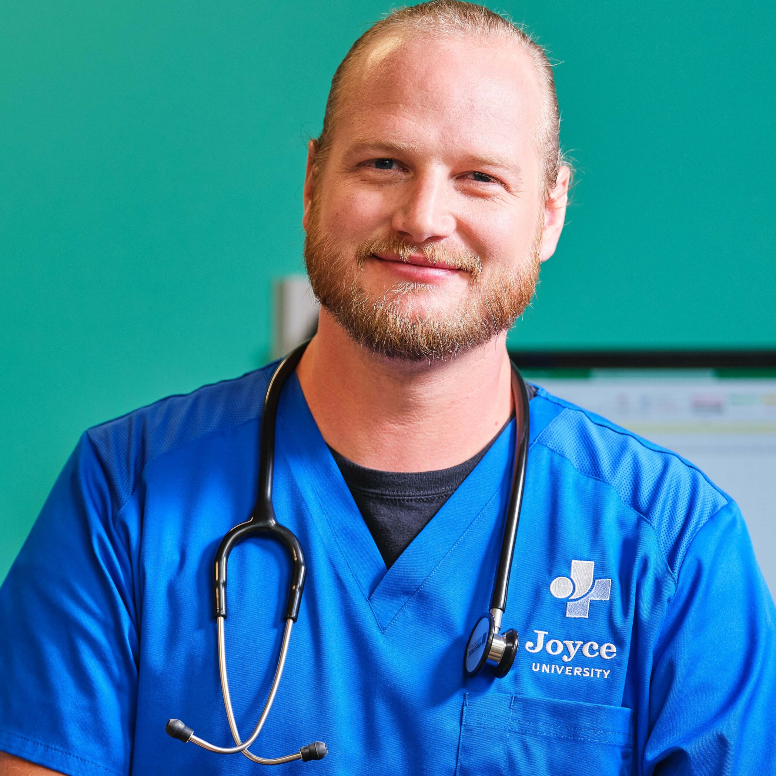 male nursing student in blue joyce university scrubs standing in simulation center