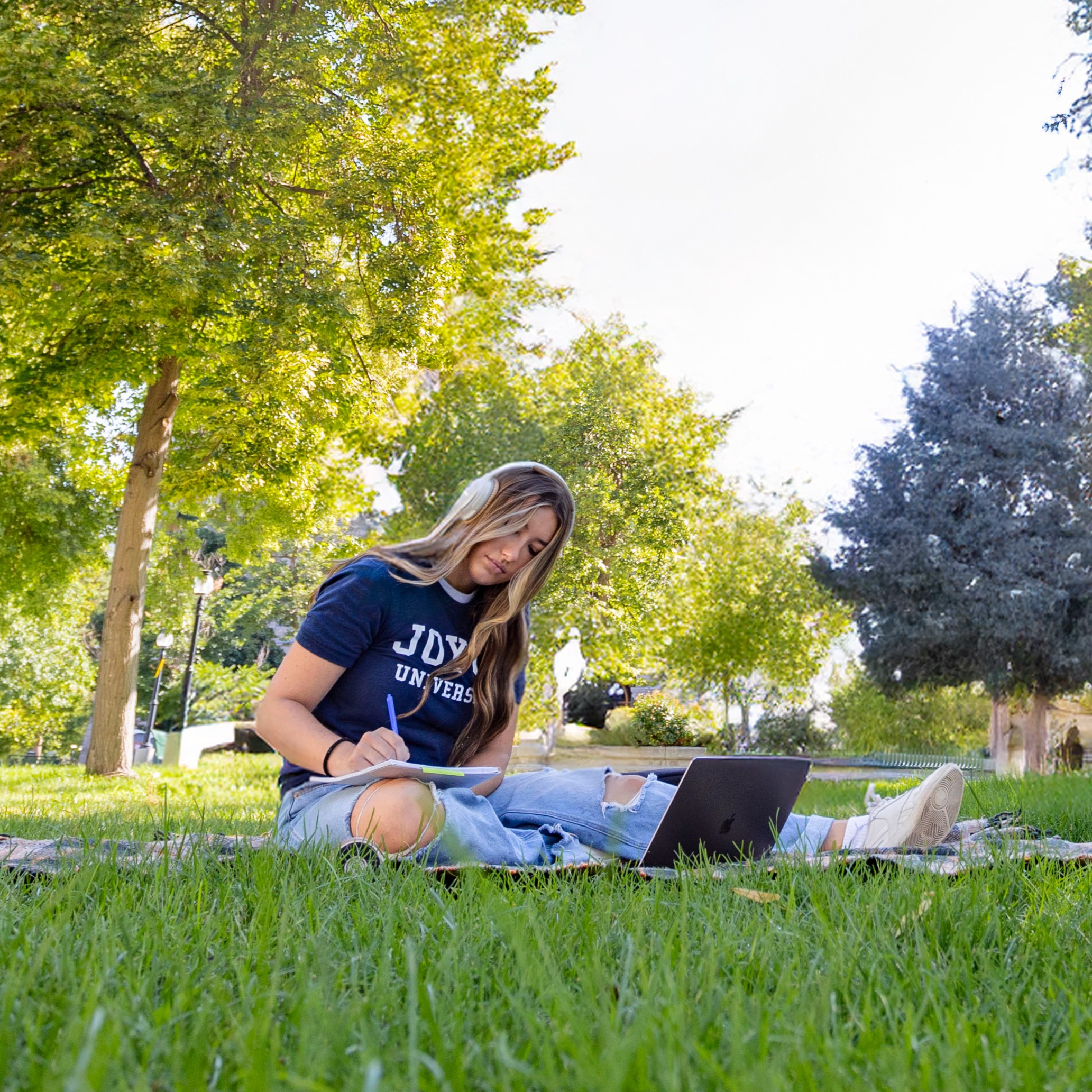 Joyce University student in South Carolina sitting in a park studying on a laptop